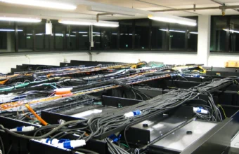 Overhead cable trays and power connectors above a row of data center server racks