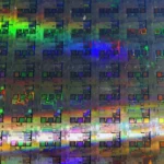 A 12-inch silicon wafer showing rows of unfinished chip dies under iridescent light