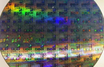 A 12-inch silicon wafer showing rows of unfinished chip dies under iridescent light