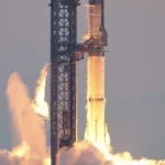 SpaceX Starship and Super Heavy booster igniting engines at liftoff from the launch tower at Starbase, Texas, with bright exhaust flames and rising smoke clouds