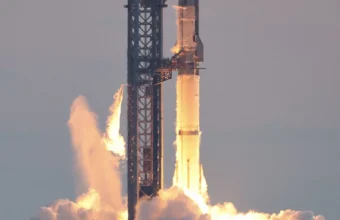 SpaceX Starship and Super Heavy booster igniting engines at liftoff from the launch tower at Starbase, Texas, with bright exhaust flames and rising smoke clouds
