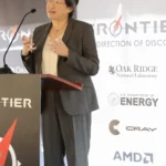 AMD chair and CEO Lisa Su speaking at a podium with AMD and Oak Ridge National Laboratory signage in the background