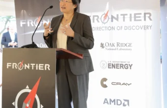 AMD chair and CEO Lisa Su speaking at a podium with AMD and Oak Ridge National Laboratory signage in the background