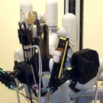 Close-up of a da Vinci surgical robot's articulated arms and instruments positioned over an operating table