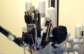 Close-up of a da Vinci surgical robot's articulated arms and instruments positioned over an operating table