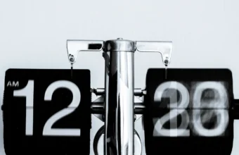 Black and white flip clock showing 12:30 AM, representing a task that runs automatically on a schedule