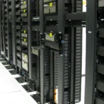 A data center aisle showing a long row of rack-mounted network switches, patch panels, and cabling