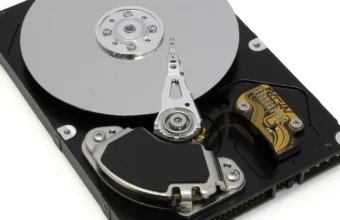 An open 3.5 inch hard disk drive with the top cover removed, showing the spinning platter, read/write head, and actuator arm