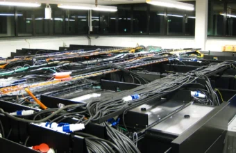 Overhead cable trays and rack-mounted servers in a data center, representing the infrastructure behind Models-as-a-Service governance