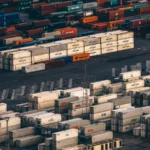 Aerial view of stacked shipping containers from many carriers at a busy container port