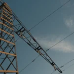 High voltage electricity transmission tower and power lines silhouetted against an evening sky