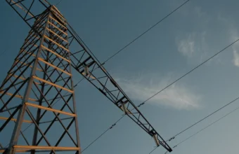 High voltage electricity transmission tower and power lines silhouetted against an evening sky
