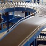 A curved industrial roller conveyor system branching into multiple paths inside a factory