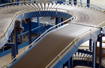 A curved industrial roller conveyor system branching into multiple paths inside a factory