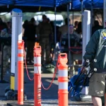 Security personnel and a walk-through scanner screening people at a checkpoint