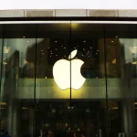 Illuminated Apple logo above the glass entrance of an Apple Store in Beijing, China