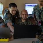 U.S. Marines from a red cell team review laptop screens during the Cyber Yankee 2022 cybersecurity exercise
