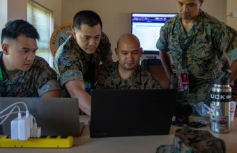 U.S. Marines from a red cell team review laptop screens during the Cyber Yankee 2022 cybersecurity exercise