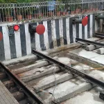 Railway tracks ending at red buffer stops beneath a covered station platform, illustrating infrastructure that reaches its limit