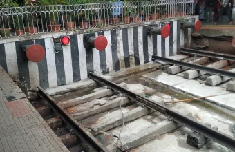 Railway tracks ending at red buffer stops beneath a covered station platform, illustrating infrastructure that reaches its limit