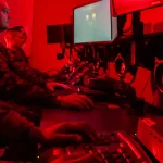 Marines at computer workstations in a red-lit cyber operations room