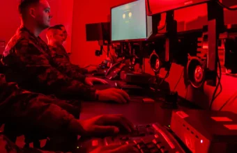 Marines at computer workstations in a red-lit cyber operations room