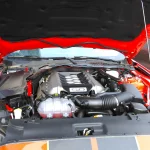 A red Mustang GT's hood raised to show its rebuilt 5.0-liter V8 engine bay