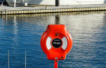 A red emergency life ring safety station mounted on a post beside a marina dock