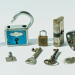 Six antique padlocks of different shapes and sizes with six mismatched keys laid out on a white background