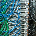 Blue and green Ethernet patch cables wired into a rack of network switches