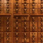 Rows of small labeled wooden drawers in a library card catalog, a visual analogy for AI memory entries organized and searchable by topic