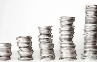 Five stacked piles of coins of increasing height against a white background