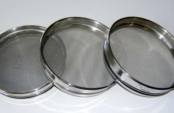 Three graduated stainless steel laboratory test sieves of decreasing mesh size, used to sort particles by size range