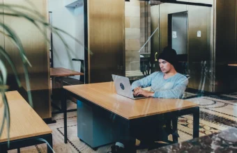 A man works on a laptop at a desk in a modern office coworking space