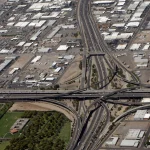 Aerial photo of a multi-level highway interchange with several lanes of traffic merging and diverging, a visual analogy for progressively shifting traffic between old and new systems during a migration
