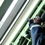 A U.S. Navy sailor uses binoculars to keep watch aboard a ship
