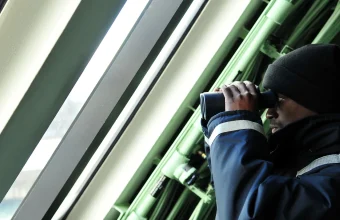 A U.S. Navy sailor uses binoculars to keep watch aboard a ship
