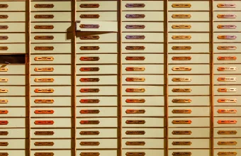 A wall of individually numbered brass safe deposit boxes in a bank vault, each with its own separate keyhole