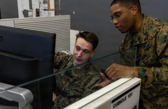 Two U.S. Marines review a monitor together in a Network and Security Operations Center at Marine Corps Base Camp Pendleton