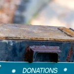 A weathered outdoor metal donation box labeled Donations Please Help