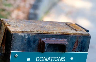 A weathered outdoor metal donation box labeled Donations Please Help