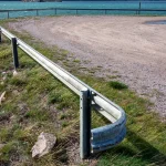 A curved steel highway guardrail running along a rocky coastline