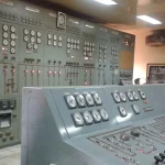 Analog gauges and switches inside an industrial power plant control room, representing the critical infrastructure systems targeted by ransomware