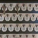 A hotel-style key board with numbered tags, some slots holding keys and others empty