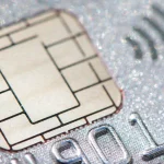 Macro close-up of a gold EMV smart card chip and contactless payment symbol embedded in a card