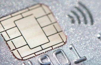 Macro close-up of a gold EMV smart card chip and contactless payment symbol embedded in a card