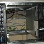 An open, empty slot with tangled cabling inside a server rack, exposed between two mounted appliances