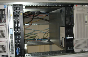 An open, empty slot with tangled cabling inside a server rack, exposed between two mounted appliances