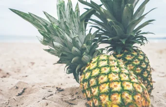 Two whole pineapples resting on sand at the beach, a literal nod to Cloudflare's internal codename Big Pineapple for its DNS platform