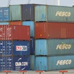 Stacked, brightly colored shipping containers from multiple carriers at a busy container terminal